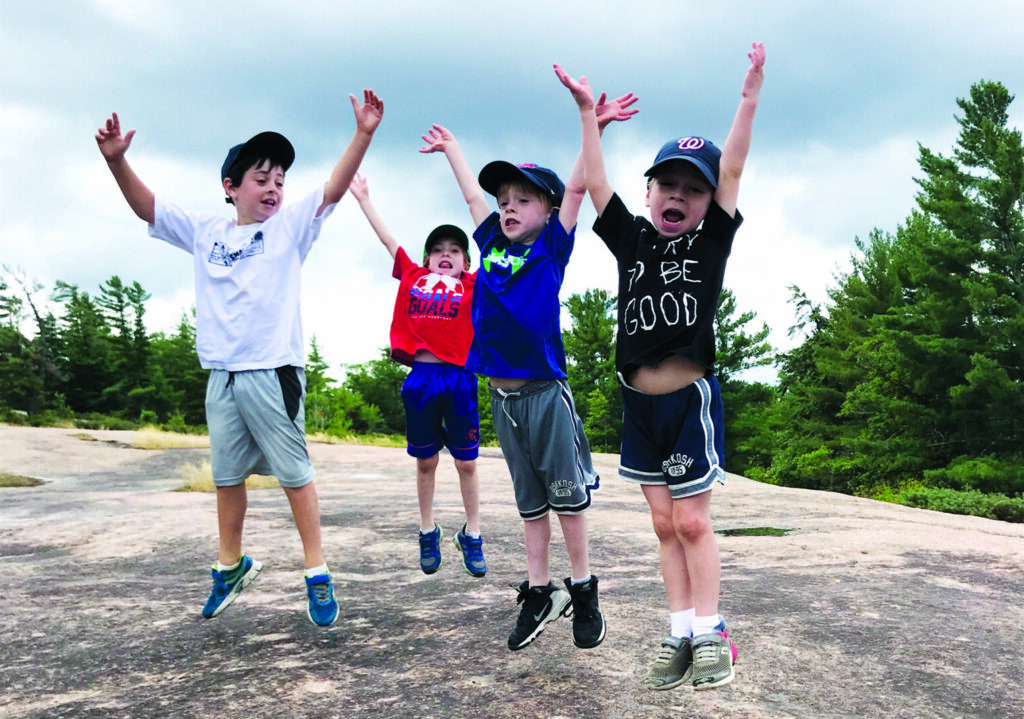 four kids holding their arms up